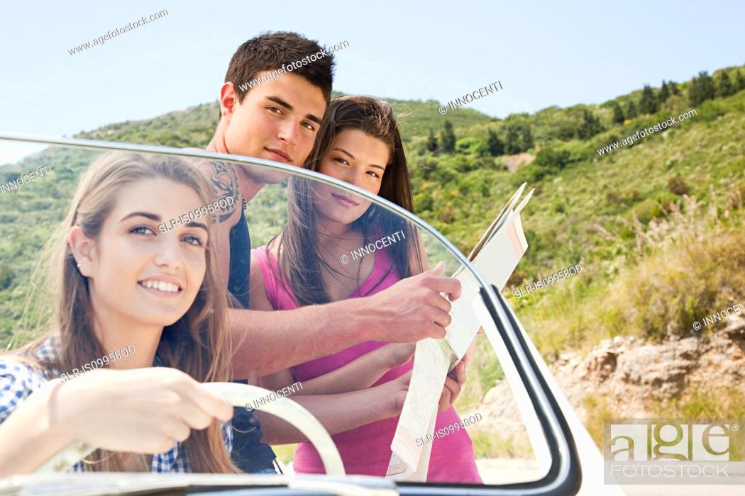 Stock Photo: Young friends with convertible car looking at map.