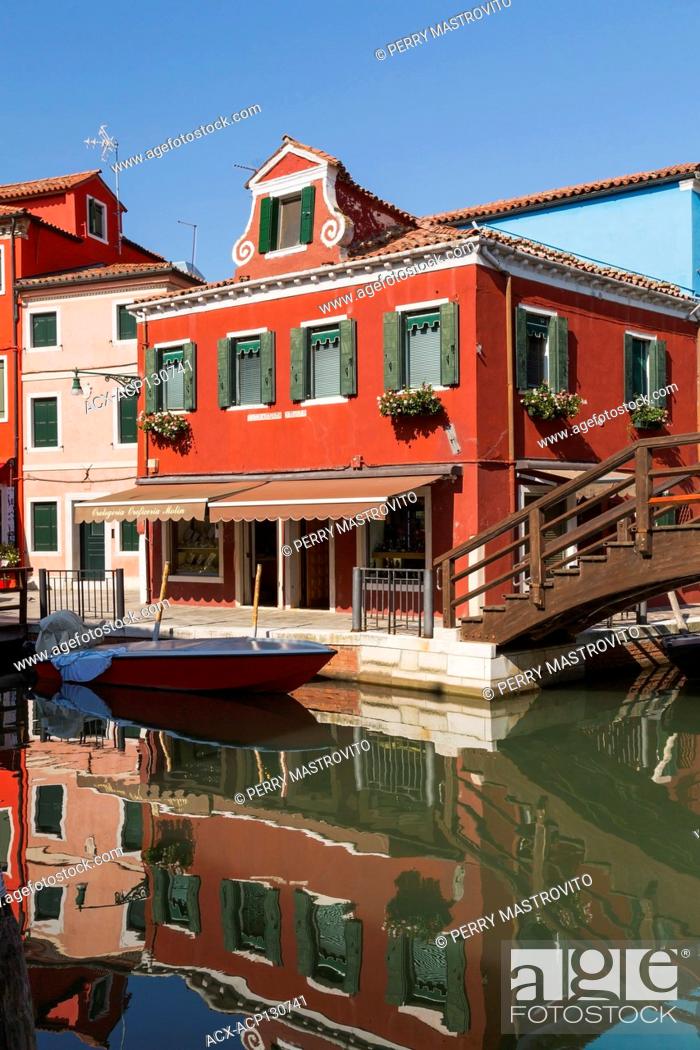 Stock Photo: Brown wooden footbridge over canal with moored boat and pink and red stucco houses and a storefront, Burano Island, Venetian Lagoon, Venice, Veneto, Italy.