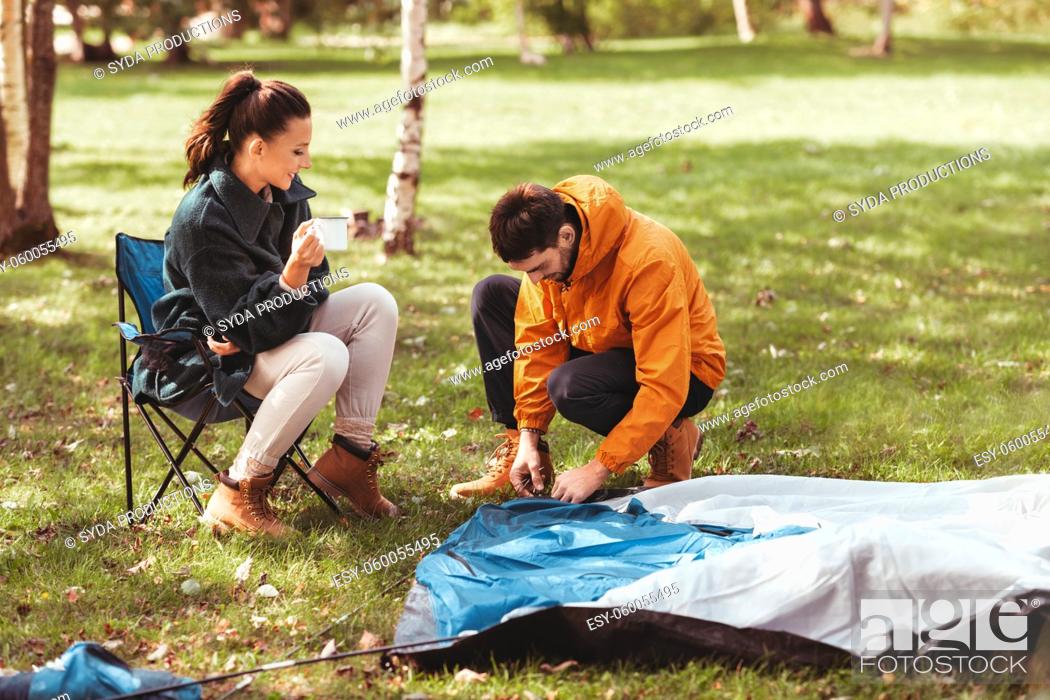Stock Photo: happy couple setting up tent outdoors.