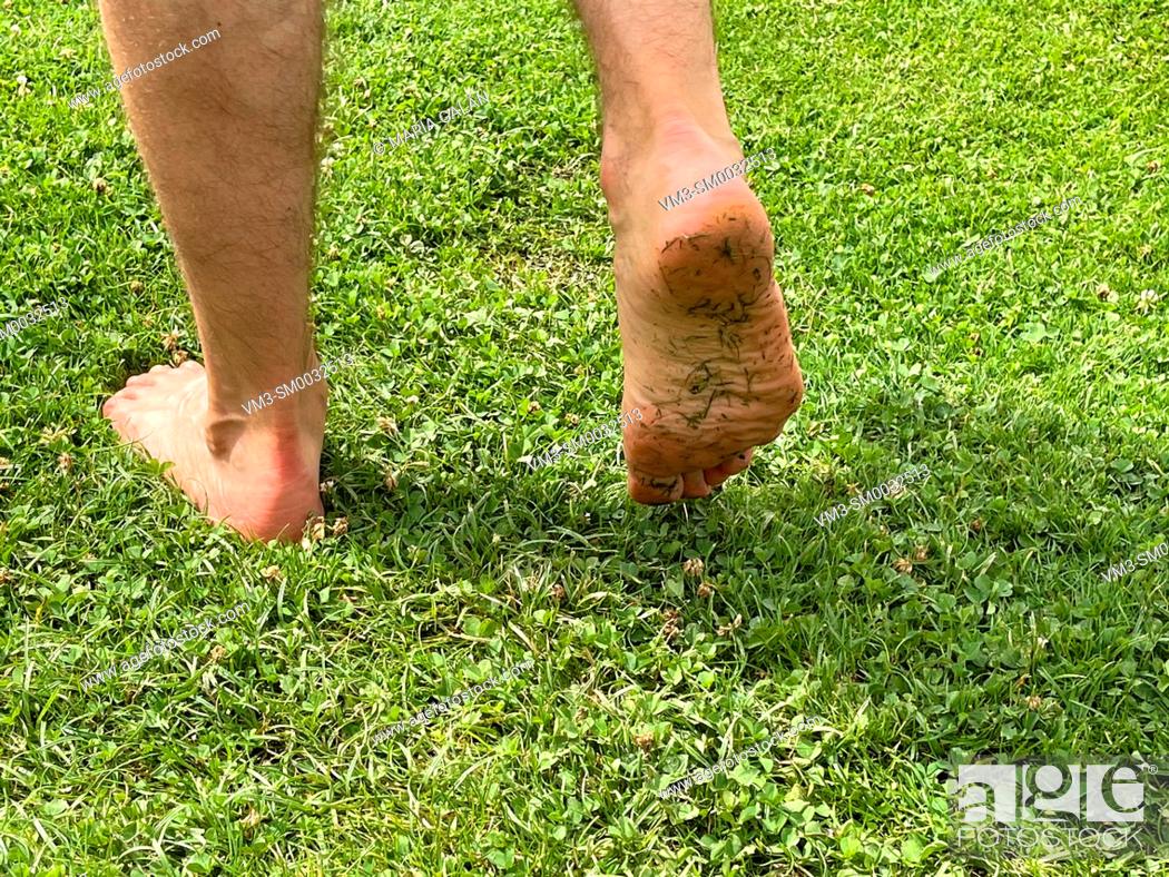 Stock Photo: Man walking barefoot on grass.