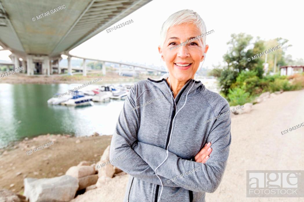 Stock Photo: Smiling Senior Woman Relax Listening Music With Earphones After Running, Gray-Short Hair, Wear Sports clothes , Workout Outdoor.