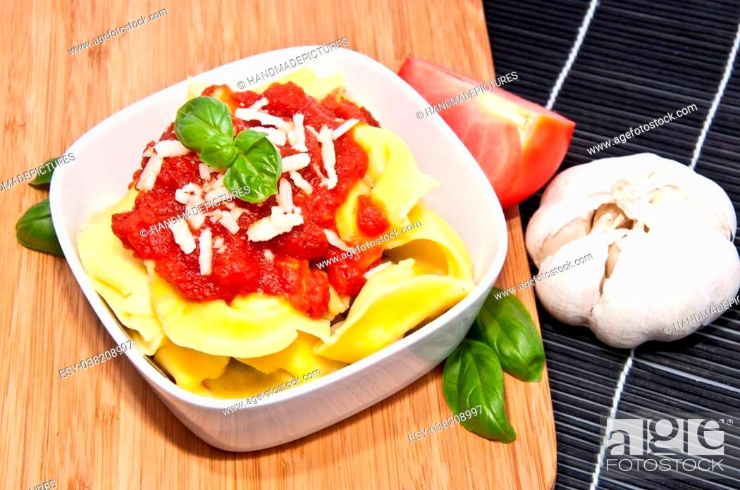 Stock Photo: Tortellini in a bowl with ingredients on a black tablecloth.