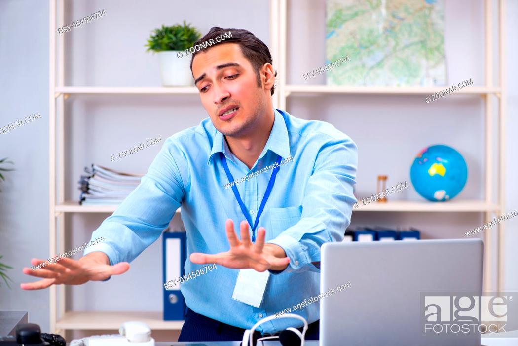 Photo de stock: The young male travel agent working in the office.