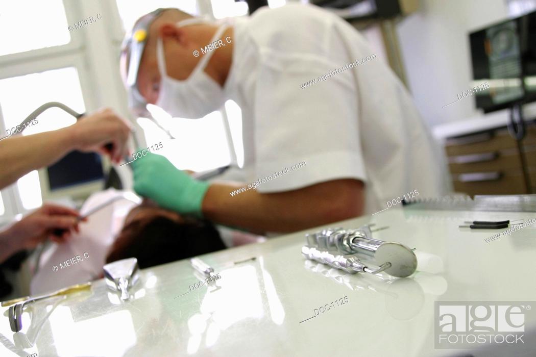 Stock Photo: Dentist cutlery im Vordergrund, dentist abrades teeth of a lying patient in the background.