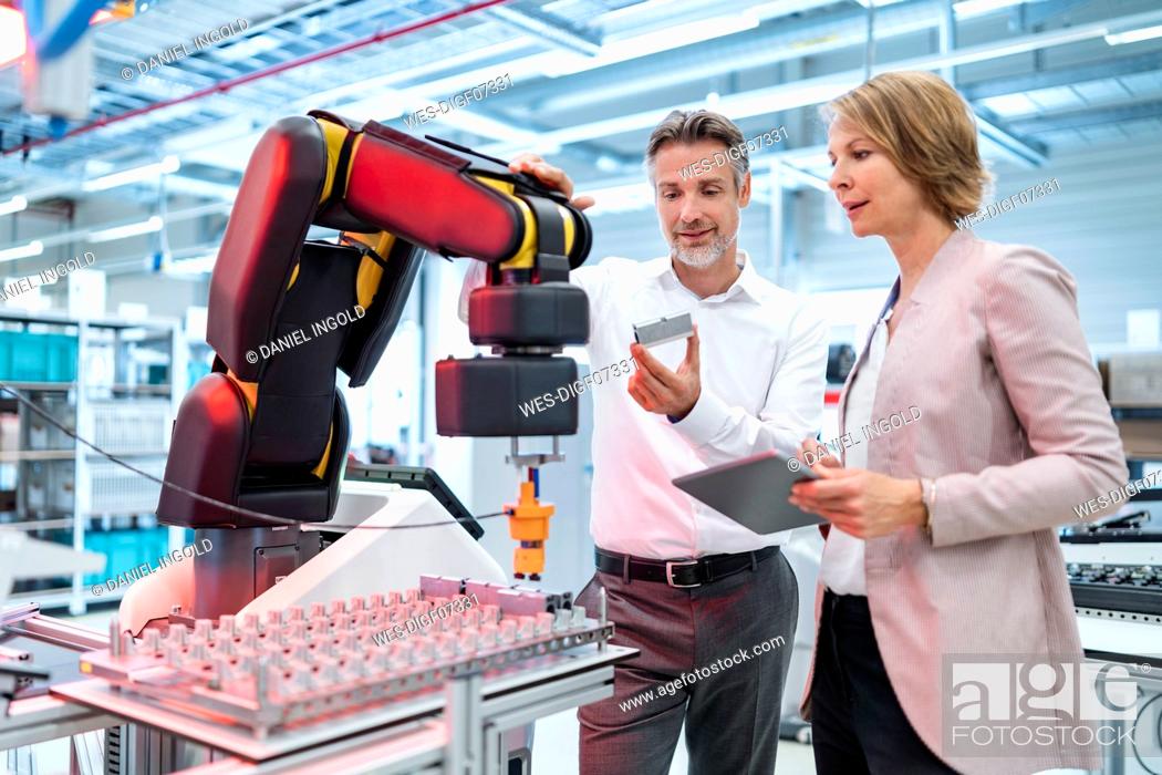Stock Photo: Businessman and businesswoman talking in a modern factory hall.