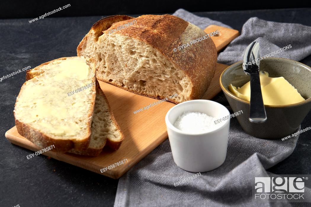 Stock Photo: close up of bread, butter, knife and salt on towel.