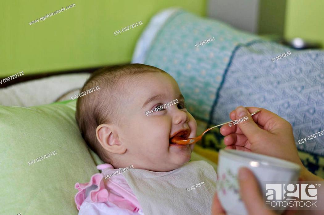 Stock Photo: A young child is looking into the camera and sucking feeding-bottle. The baby has bright blue eyes.