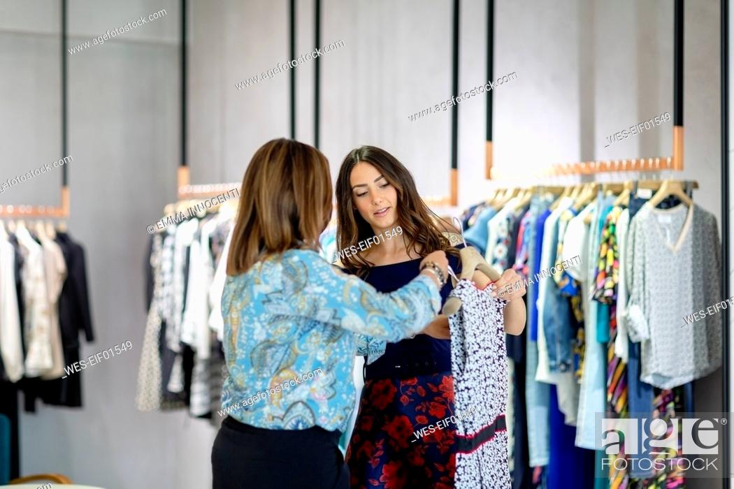 Stock Photo: Female shopkeeper assisting woman while holding dress in boutique.