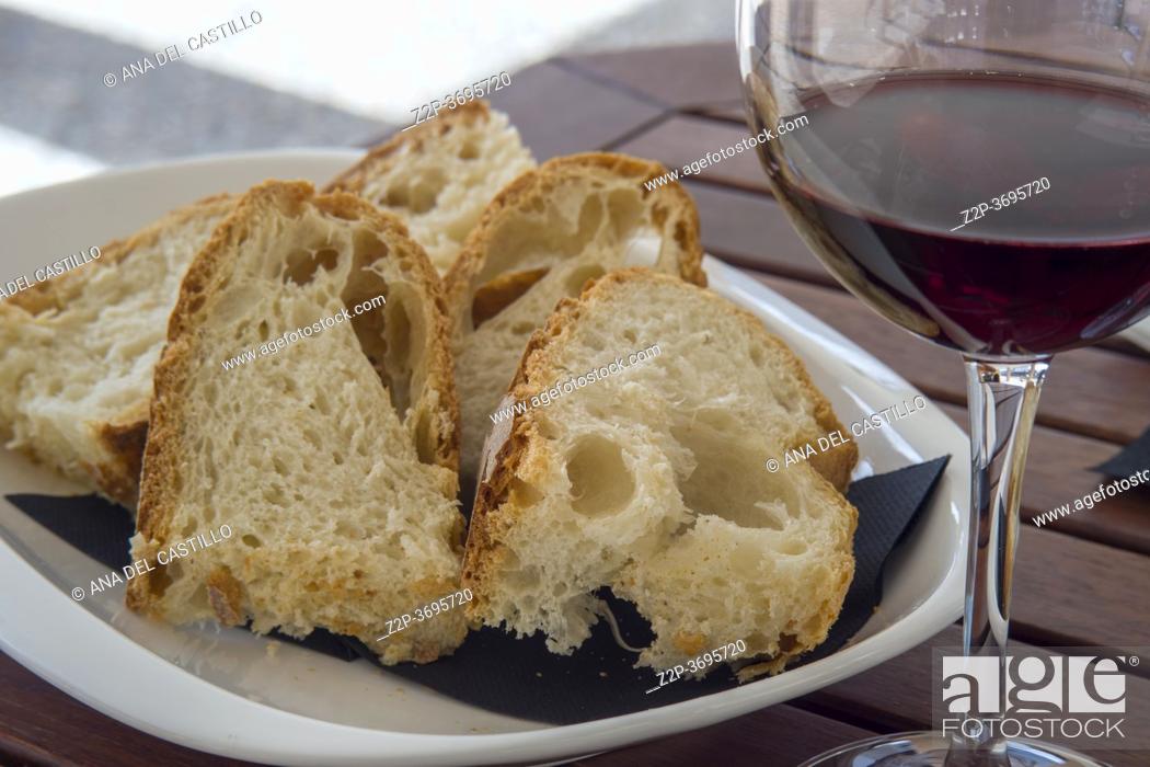 Stock Photo: Glass of red wine and slices of homemade bread on plate in outdoor restaurant Spain.