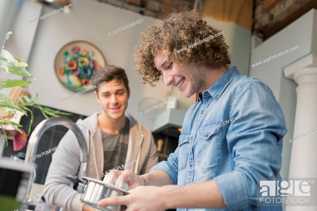 Photo de stock: Young men roommates cooking in kitchen.