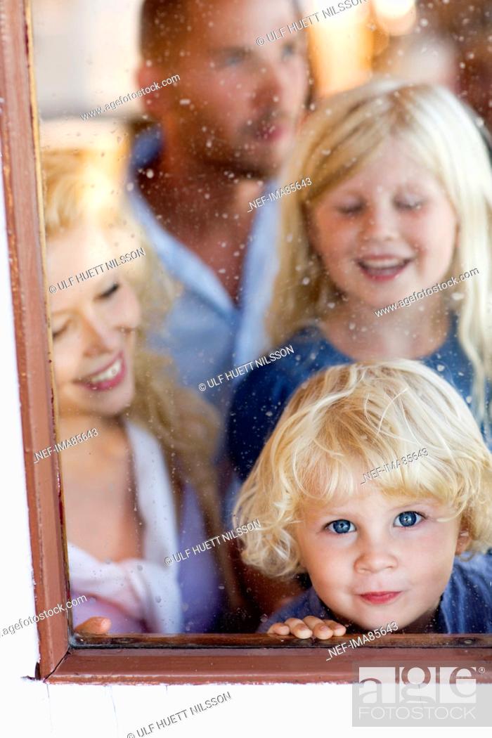 Stock Photo: Family standing beside window, smiling.