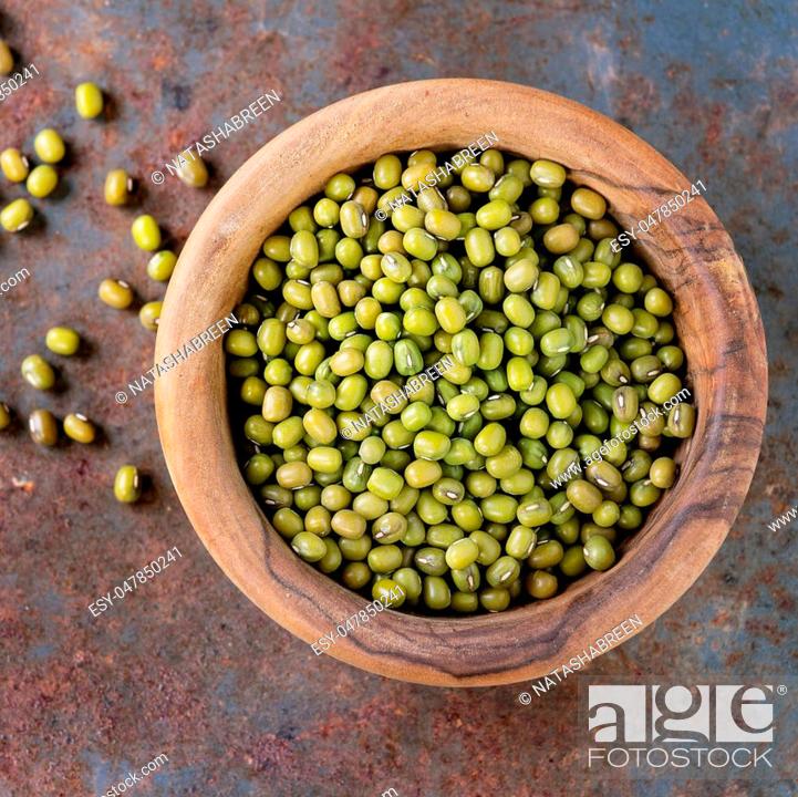 Stock Photo: Healthy superfood. Uncooked green mungo beans in olive wood bowl over old rusty iron background. Top view. Close up. Square image.