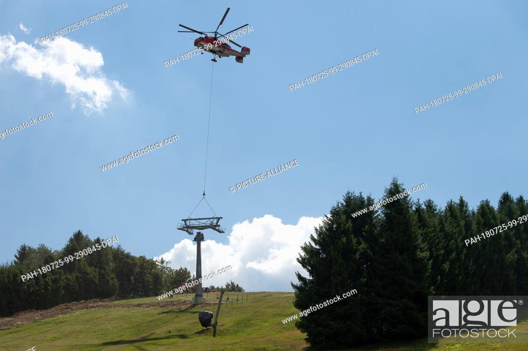 Stock Photo: 25 July 2018, Willingen, Germany: Parts of a chairlift support of the new 8-seater chairlift ""K1 Willingen"" on the Köhlerhagen runway are transported with the.