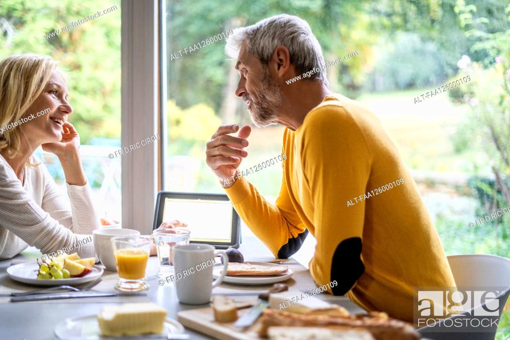 Stock Photo: Smiling mature couple talking with each other while having breakfast.
