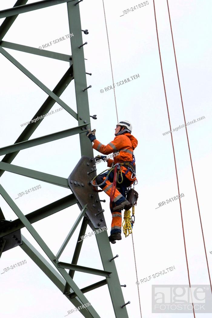 Stock Photo: Lineman working with a wire rope hoist on a 380-kV long-distance line owned by the 50Hertz transmission system operator, track cables are being pulled from one.