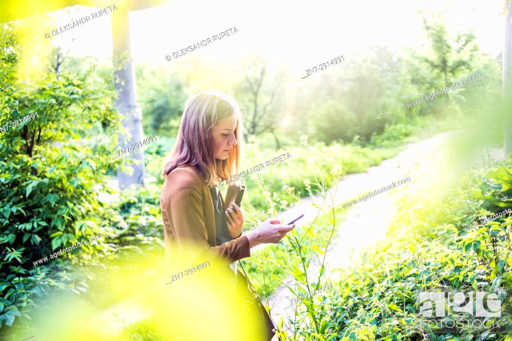 Stock Photo: Woman looking at mobile phone outdoors.