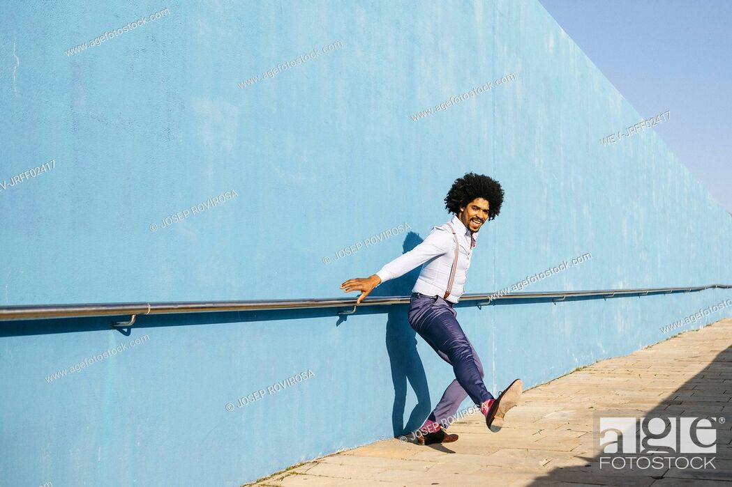 Stock Photo: Man dancing in front of blue wall.