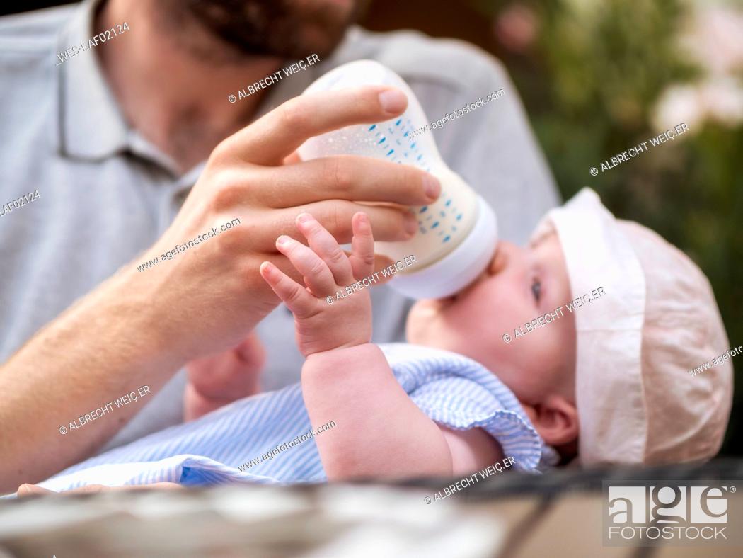 Stock Photo: Father bottle-feeding baby girl.