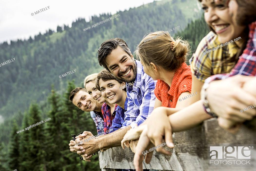 Stock Photo: Group of friends leaning on wooden fence, Tirol, Austria.