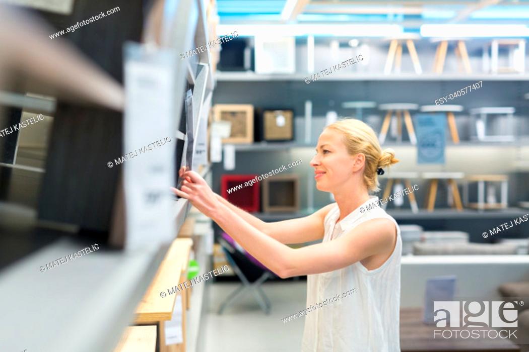 Stock Photo: Beautiful young caucasian woman choosing the right item for her apartment in a modern home decor furnishings store. Shopping in retail store.