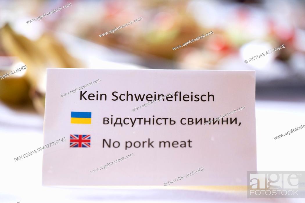 Stock Photo: 17 August 2022, Saxony, Dresden: A sign reading ""No pork"" is displayed in German, Ukrainian and English at a buffet on a table.