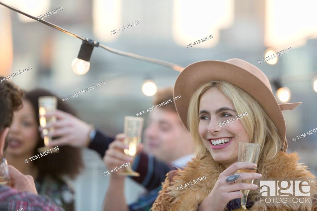 Stock Photo: Smiling young woman drinking champagne at party.