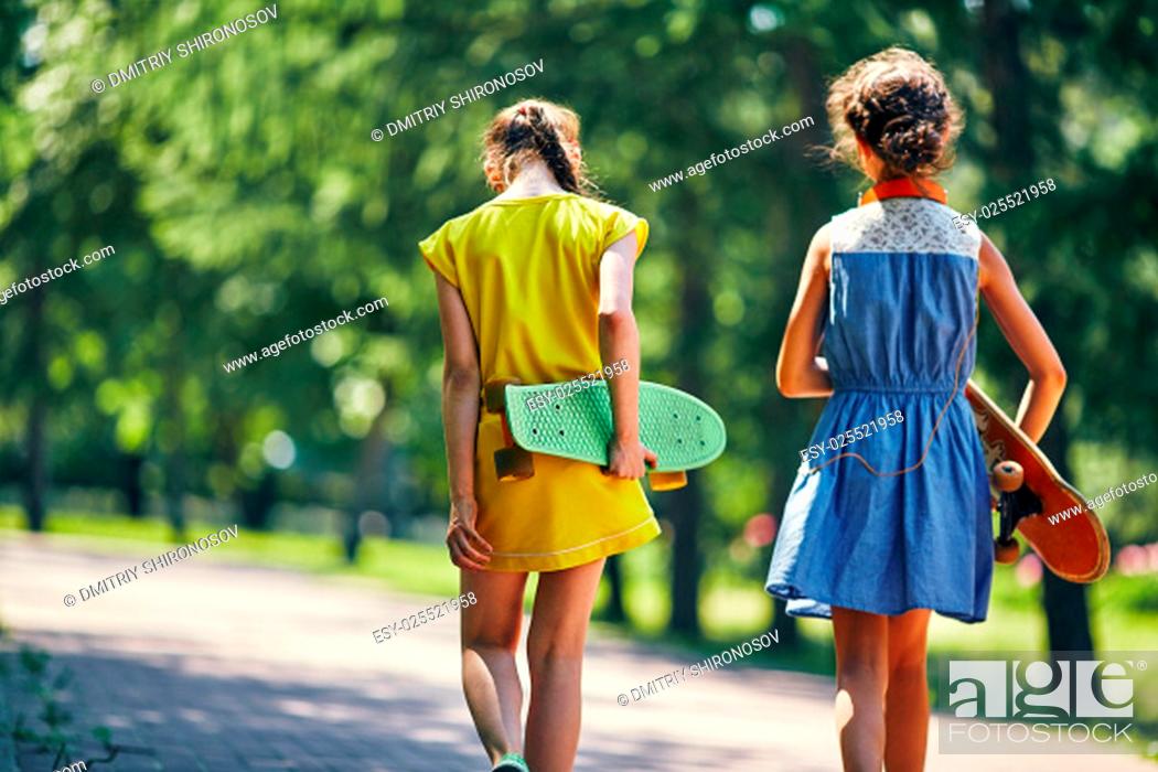 Stock Photo: Backs of girls carrying skateboards.