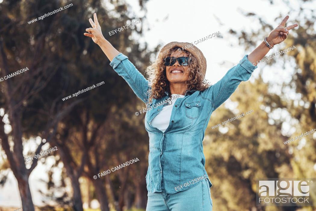 Photo de stock: Overjoyed people happy woman raising her arms with victory gesture and smiling with green trees nature outdoors background.