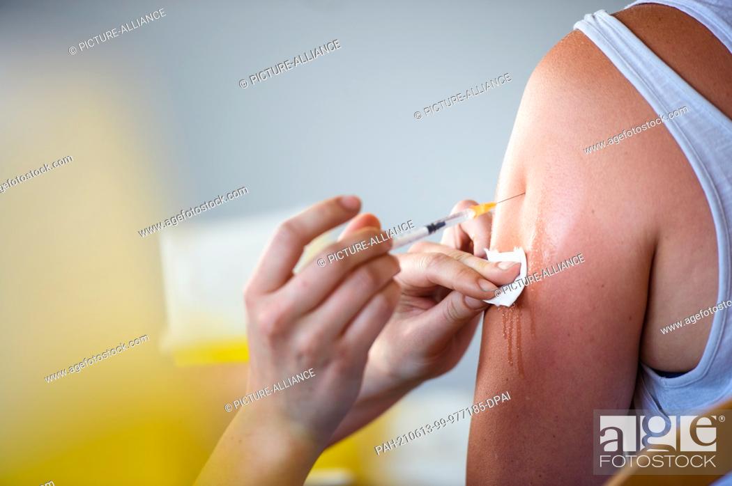 Stock Photo: 13 June 2021, Mecklenburg-Western Pomerania, Wismar: A woman is vaccinated against the coronavirus with the Johnson & Johnson vaccine by a doctor's assistant in.