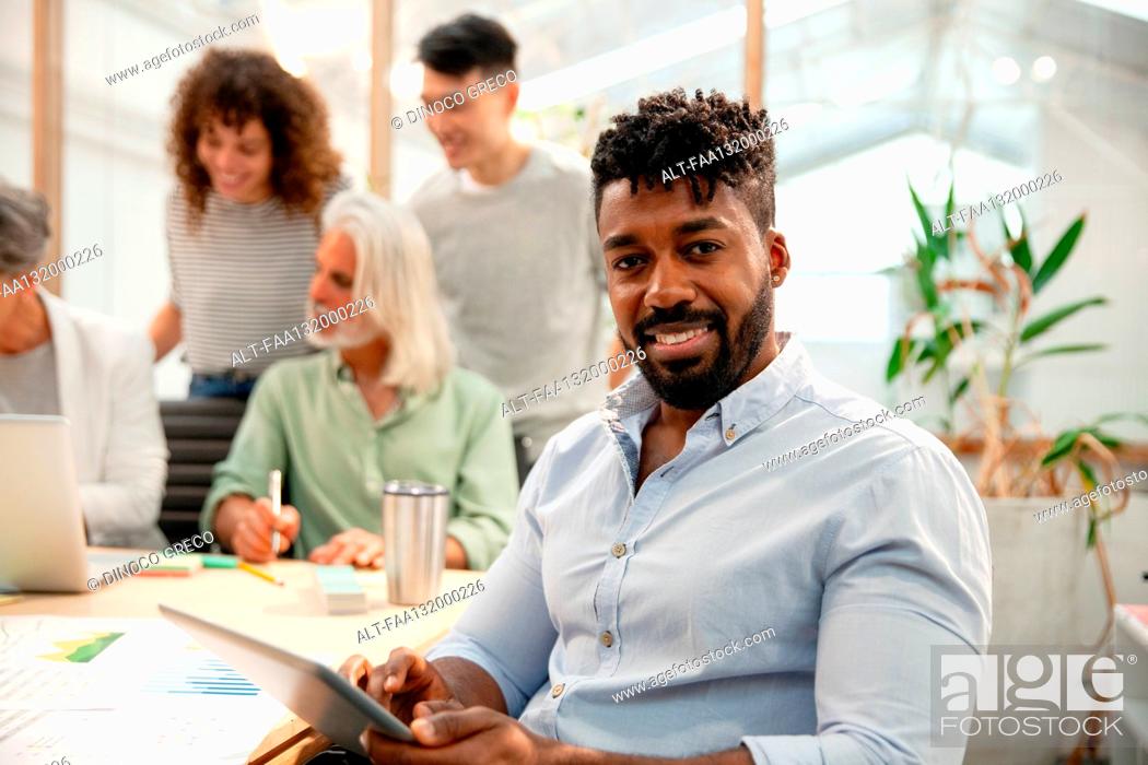 Photo de stock: African American businessman using digital tablet while looking at the camera.