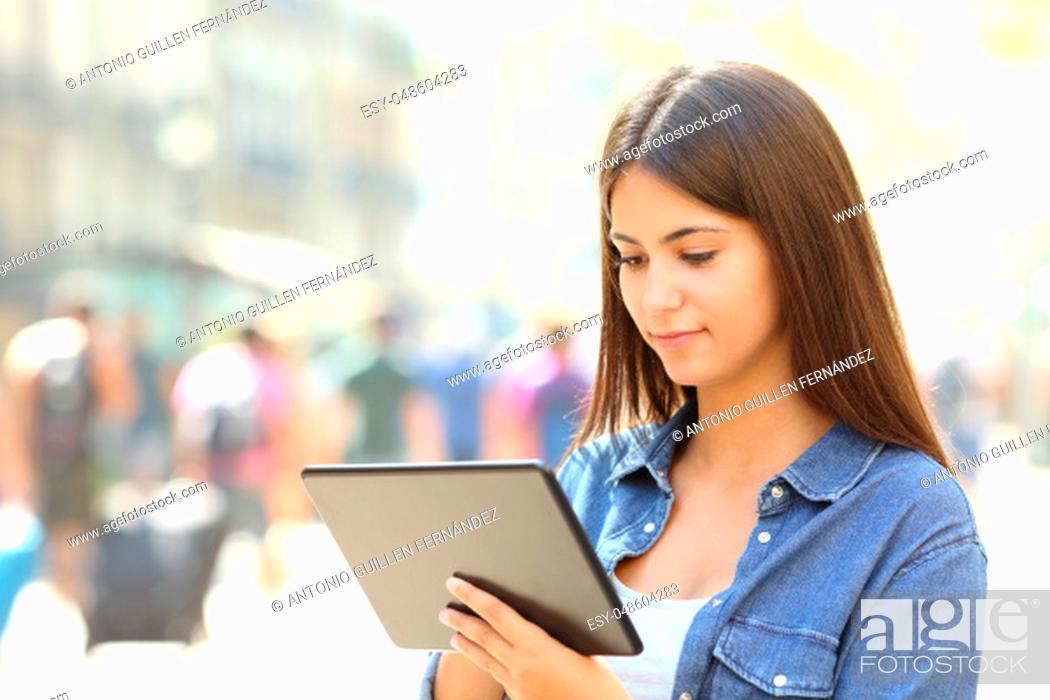 Stock Photo: Serious teen is using a tablet in the street.