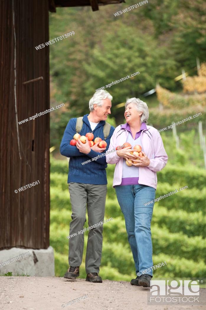 Stock Photo: Italy, South Tyrol, Mature couple carrying apples, smiling.