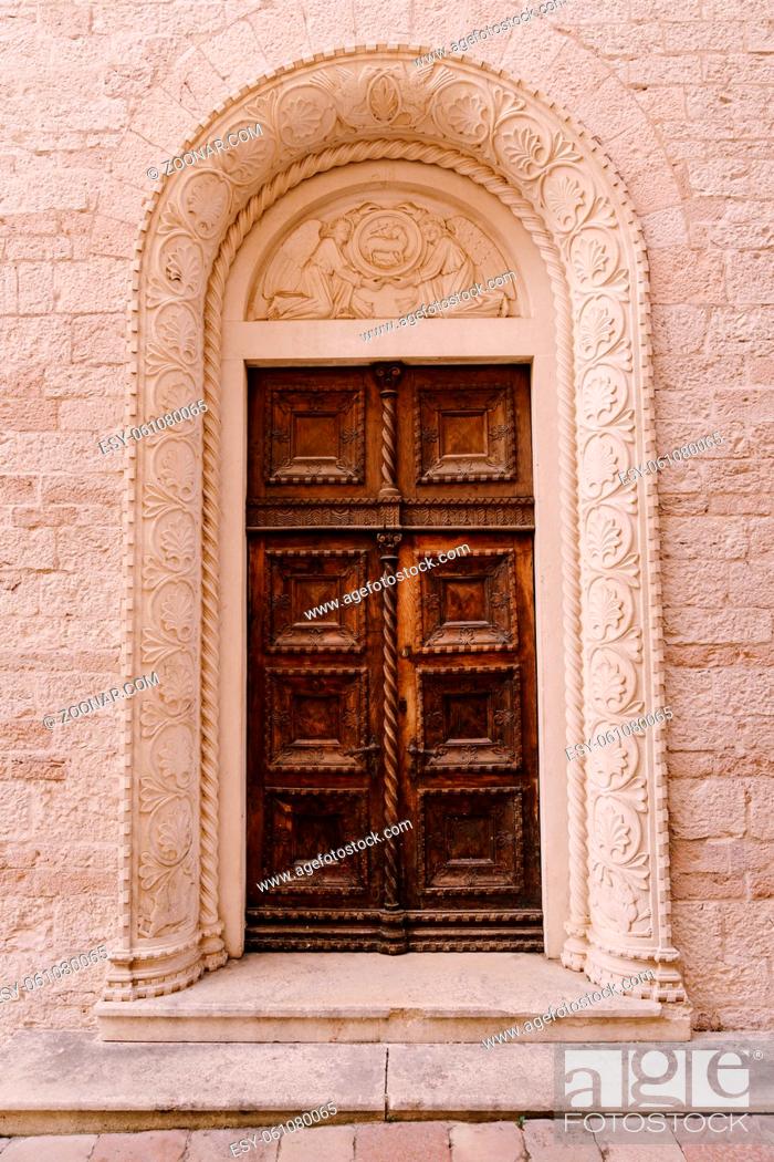 Stock Photo: Brown doors to the temple, with patterns in the arch with patterns, under the molding with the image of angels. High quality photo.