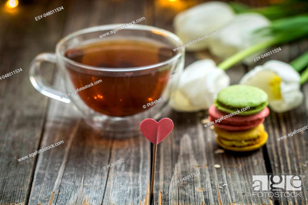 Stock Photo: beautiful white tulips and a transparent Cup of tea with a macaron on wooden background, holiday concept.