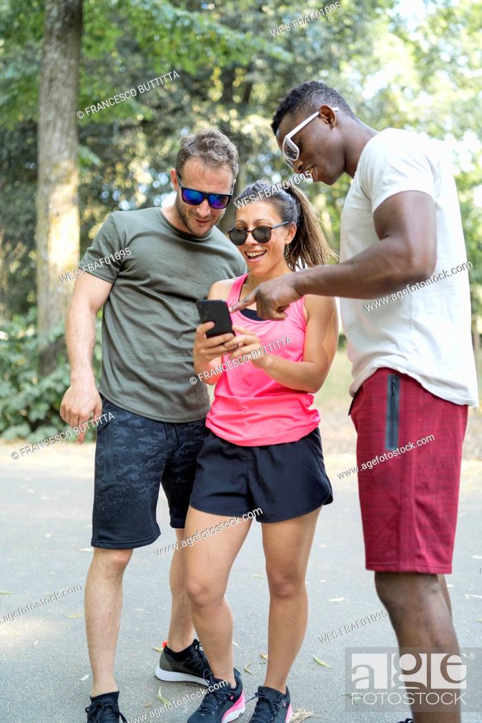Imagen: Friends having a break from exercising looking at smartphone.