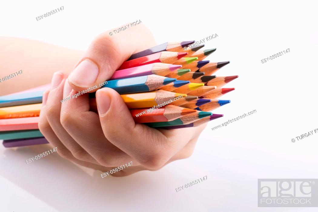 Imagen: Hand holdin color pencils on a white background.