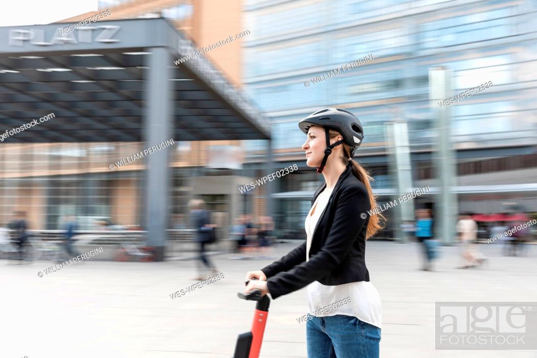 Stock Photo: Woman riding e-scooter in the city, Berlin, Germany, Berlin, Germany.