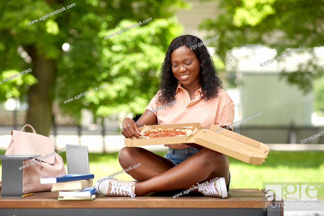 Stock Photo: african student girl eating takeaway pizza in city.