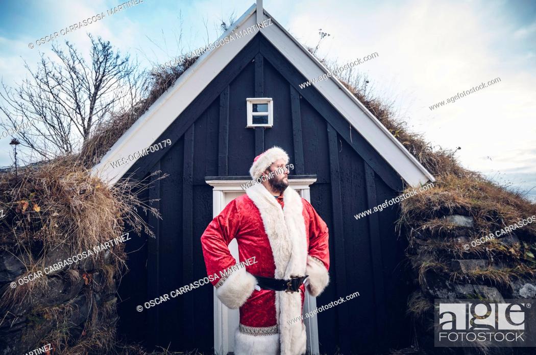 Stock Photo: Iceland, Santa Claus standing in front of cabin looking at distance.