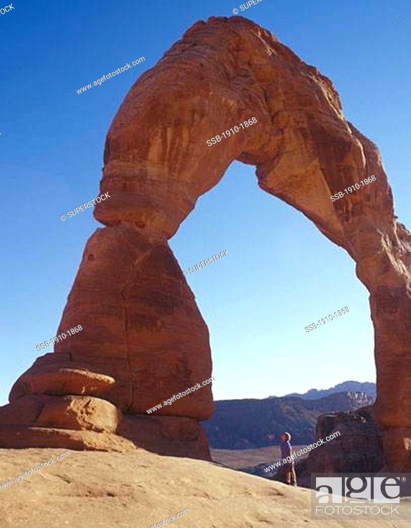Stock Photo: Young boy 10 standing on rock below Delicate Arch Arches Natl Park USA Utah.