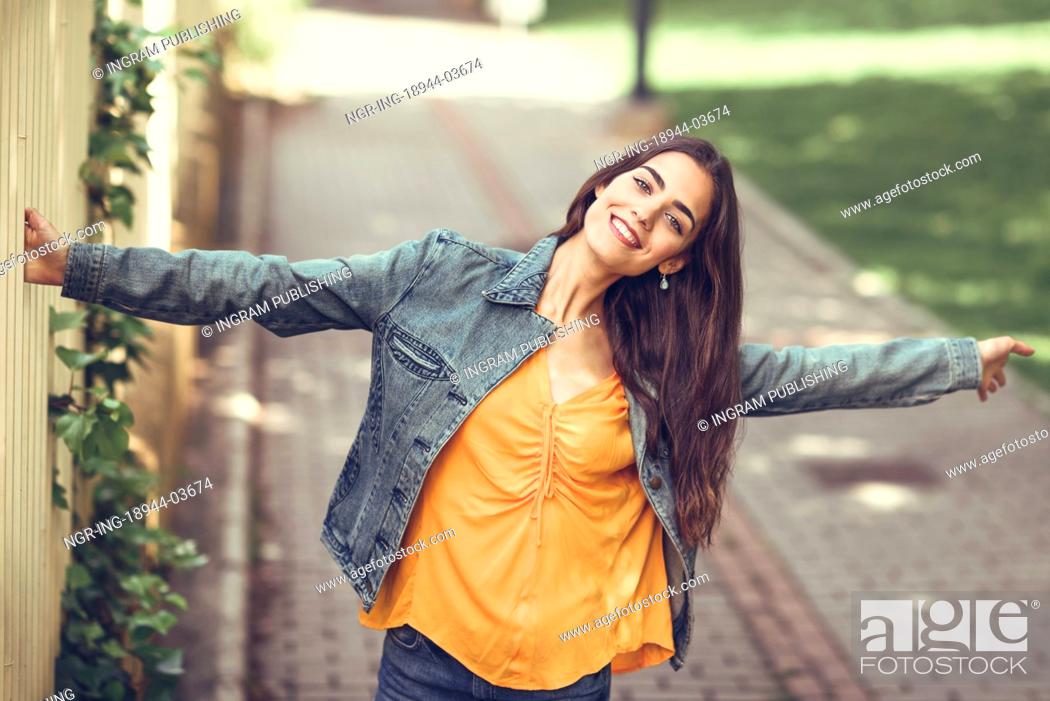 Photo de stock: Young woman with nice hair wearing casual clothes in urban background. Happy girl with wavy hairstyle.