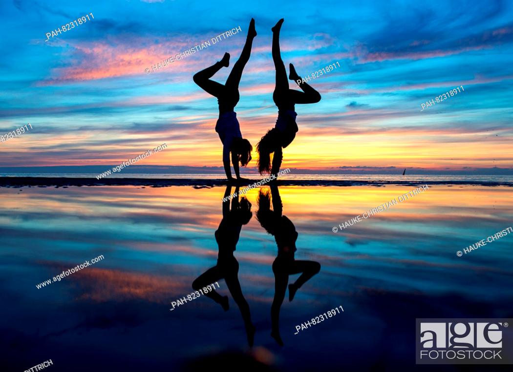 Stock Photo: Liske and Pia doing a handstand during sundown on the beach of Norderney island, Germany, 26 July 2016. PHOTO: HAUKE-CHRISTIAN DITTRICH/dpa | usage worldwide.