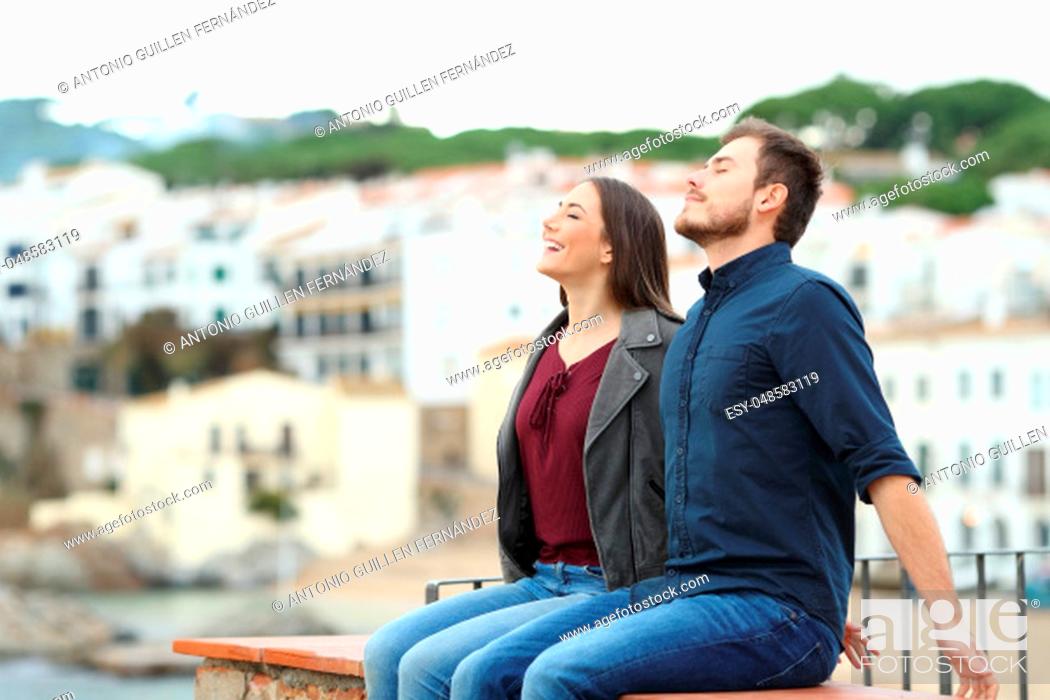 Stock Photo: Happy couple breathing fresh air on a ledge on vacation in a coast town.