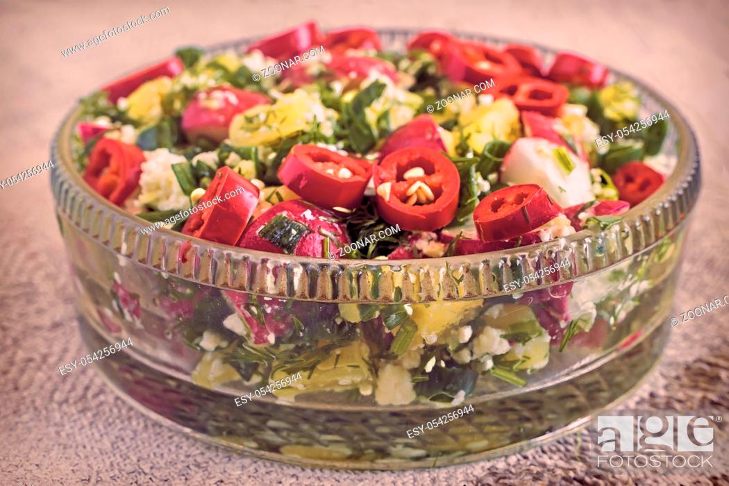 Imagen: In a glass dish salad of fresh radish, potatoes, green onions, chili, cottage cheese. Presented close-up.