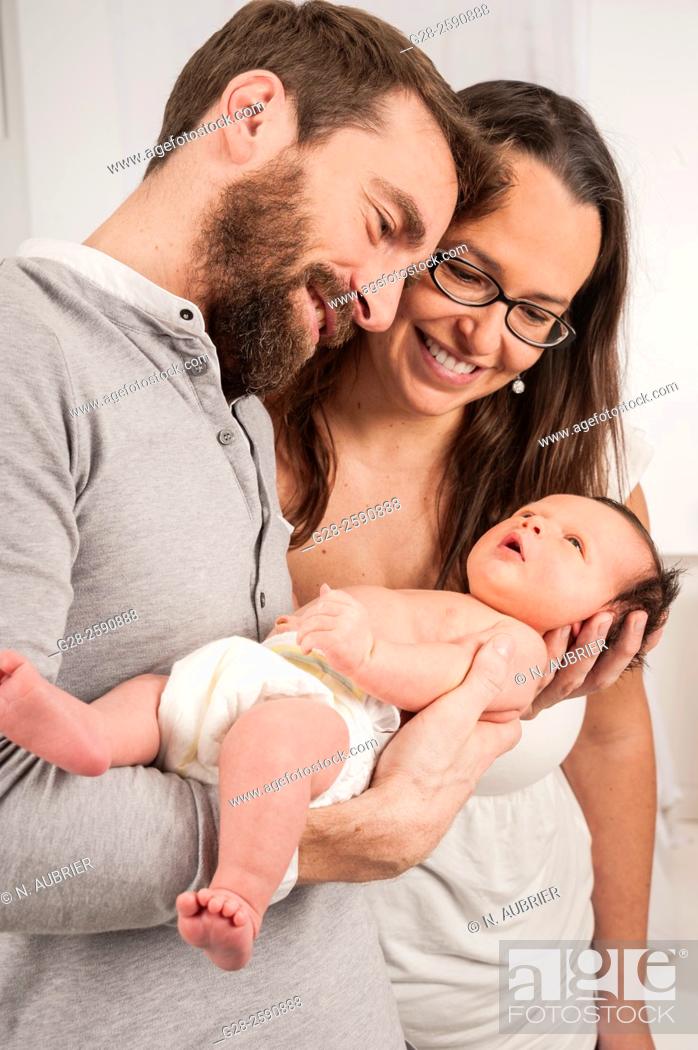 Stock Photo: Happy and proud parents holding their newborn baby boy and smiling.