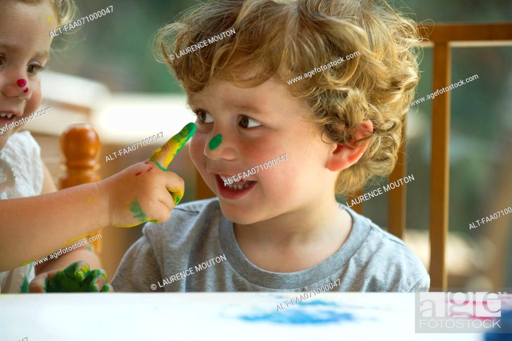 Stock Photo: Little girl wiping paint on her brother's face.