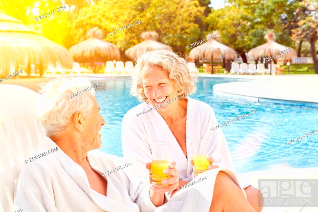 Stock Photo: Glückliches Paar Senioren sitzt mit Orangensaft im Wellness Urlaub am Hotel Pool.