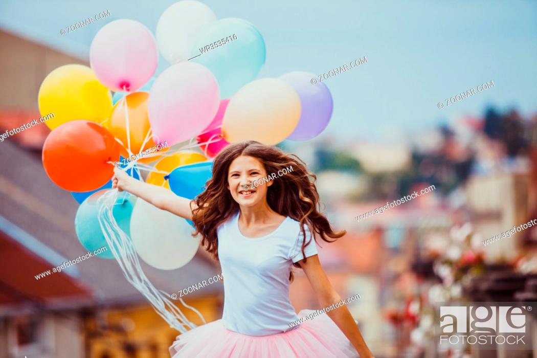 Stock Photo: Pretty girl with big colorful latex balloons posing in the street of an old town.