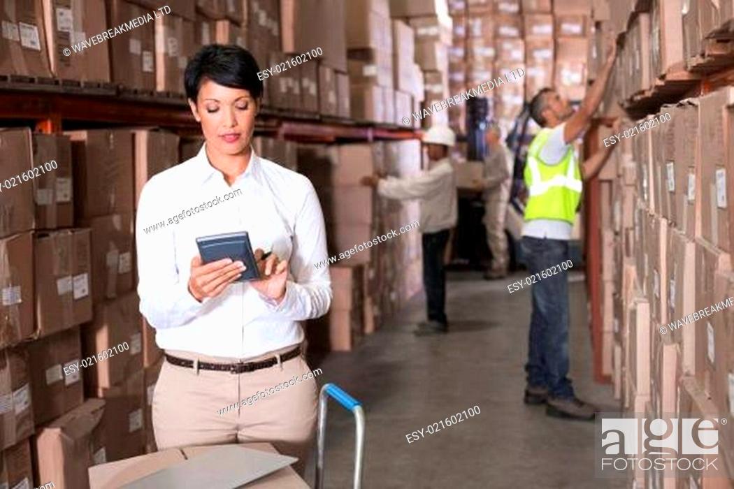 Stock Photo: Pretty warehouse manager using calculator.