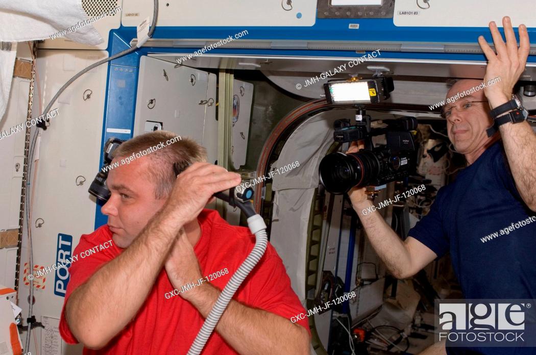 Stock Photo: Russian cosmonaut Maxim Suraev, Expedition 21 flight engineer, trims his hair in the Destiny laboratory of the International Space Station.